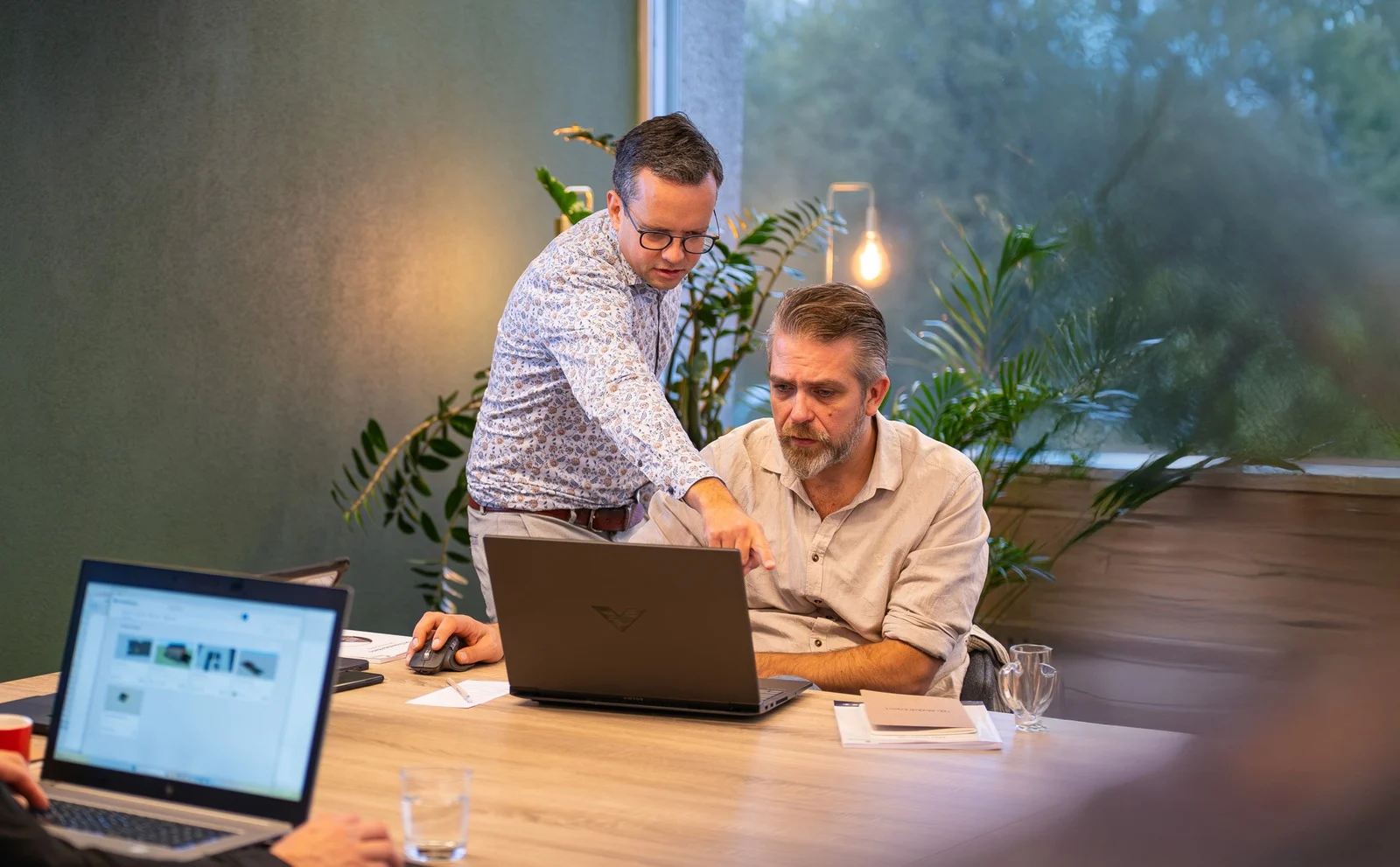 Twee collega's van SketchExpert overleggen achter de laptop